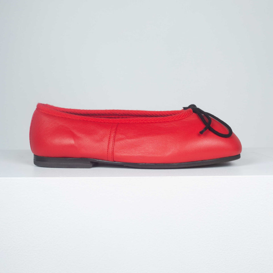 Comme des Garçons red leather ballet shoes with hard toe, black decorative bow and black slightly heeled soles.